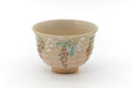 Cream matcha bowl (chawan) painted with delicate floral sprays in pink and green, three-quarter view