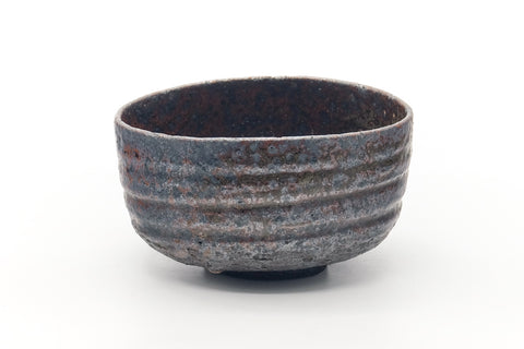 Front view of the earthy chawan showing its ribbed bands and rusty-metallic glaze.