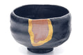 Black raku kintsugi chawan, three-quarter view highlighting the prominent gold kintsugi seam down the body