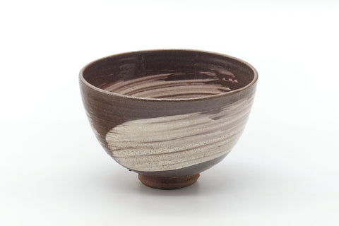 Front view of the rounded brown chawan showing the white brushed glaze over its dark surface.