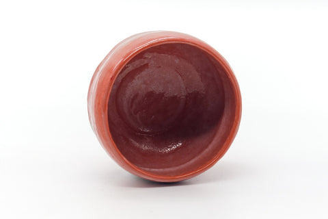 Overhead view into the bowl's deep red glazed interior.