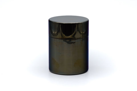 Stainless-steel tea canister, straight-on front view of the closed cylindrical canister with reflective metal surface