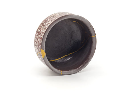 Three-quarter view from above into the dark glazed interior with gold kintsugi