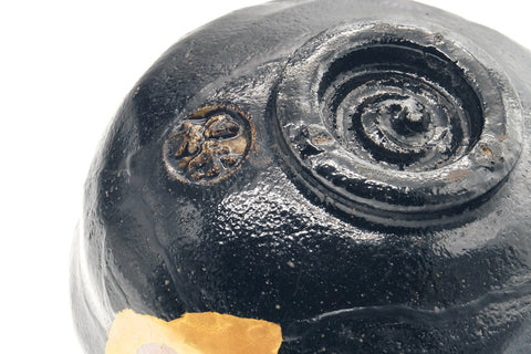 Close-up of the inverted black raku chawan base, showing the spiral-trimmed foot and gold kintsugi near the foot