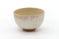 Wan-nari matcha chawan with cream-white drip glaze over reddish clay, shown from a three-quarter angle.