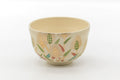 Kyo-yaki matcha bowl in cream glaze decorated with colourful painted wheat and grass motifs, shown from the front.