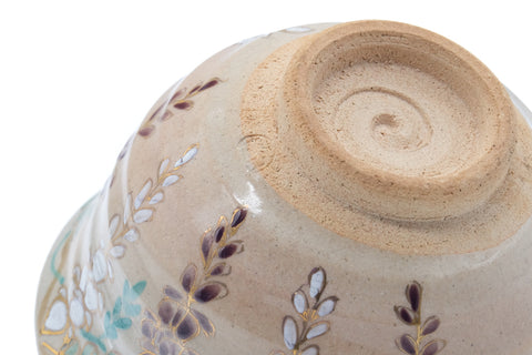 Close-up of the inverted floral chawan base, showing the spiral foot and painted blossoms near the lower body