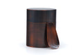 Patinated metal tea canister (chazutsu) with a matching curved tea scoop leaning against it.