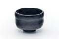 Front view of the matte-black raku bowl showing its pinched waist and small foot.