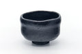 Black Raku-yaki matcha chawan with a waisted profile, shown from a three-quarter front angle.