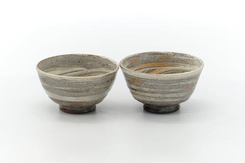 The two teacups side by side, front view, showing the marbled hakeme glaze.