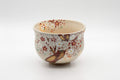 Japanese Matcha Bowl - Torasuke Kyo-yaki Komogai-nari Chawan - angled front view showing the red and white sakura blossom decoration on the cream glaze