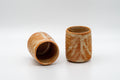 Japanese Teacups - Pair of Shino Glazed Tsutsu-gata Yunomi - 90ml - three-quarter view of the pair of ribbed orange shino cups, one tilted to show the interior