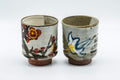 Japanese Teacups - Pair of Floral Tsutsu-gata Yunomi - 200ml - front view of the pair, one cup painted with red flowers and the other with a white lily
