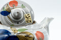 Tezumi — Floral brush-glazed kyusu teapot, angled rear view showing the side handle and fruit painting