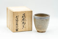 Japanese Teacup - Sadatsugu Shinjo, Sukeemon Kiln - Beige Glazed Hagi-yaki Yunomi - 150ml - front view of the teacup beside its signed paulownia box