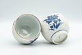 Japanese Teacups - Pair of White and Blue Floral Yunomi - 150ml - angled view with one teacup tipped to show the white glazed interior