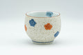 Japanese Teacup - Floral Arita-yaki Porcelain Yunomi - 150ml - front view showing the blue and orange floral painting on the speckled cream glaze