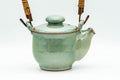 Japanese Tea Set - Green Glazed Dobin Do-ake Teapot with Katakuchi Water Cooler and 2 Yunomi Teacups - three-quarter view of the dobin showing the bamboo top handle